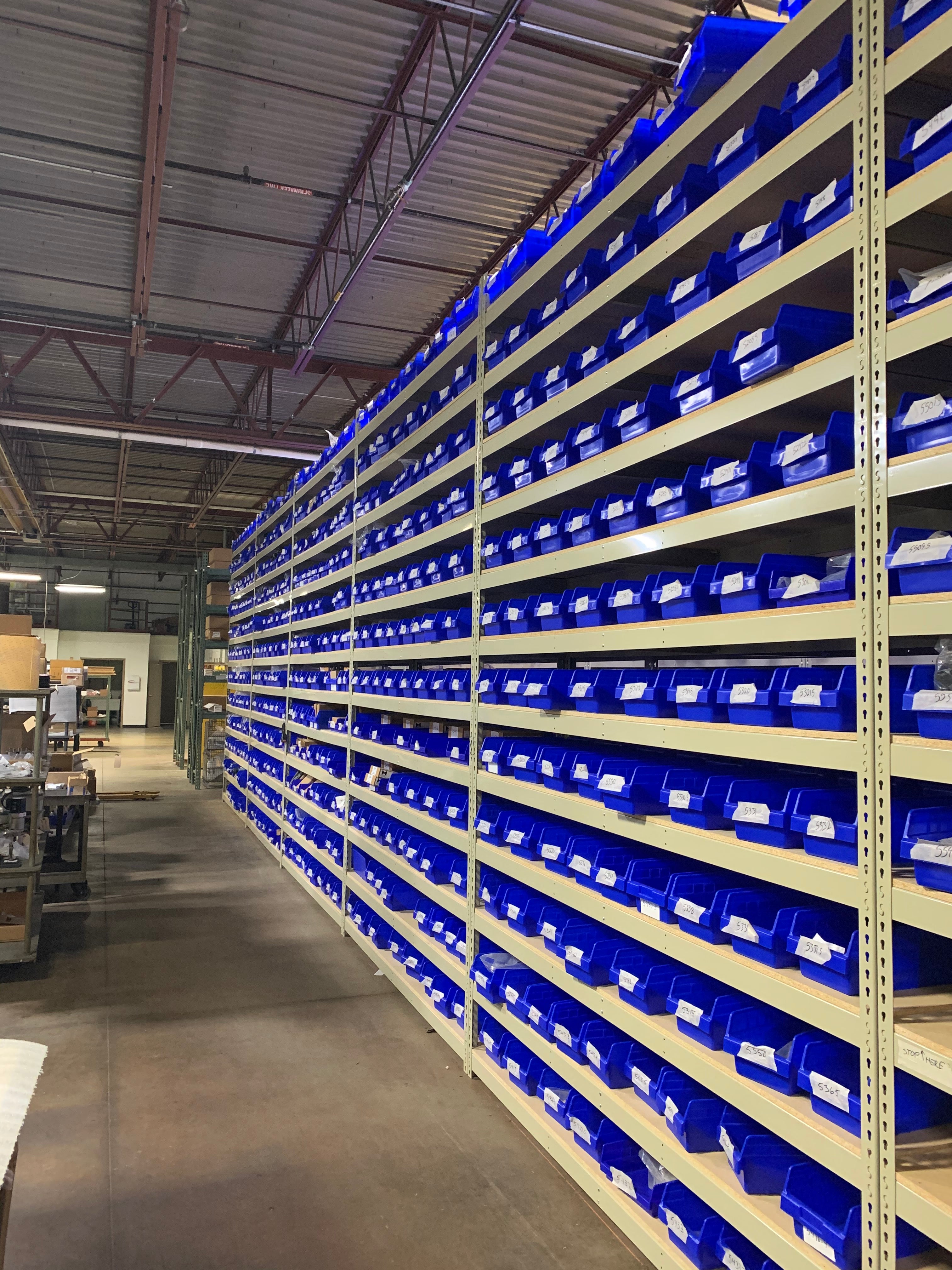 Blue bins on gray rivet shelving in a warehouse