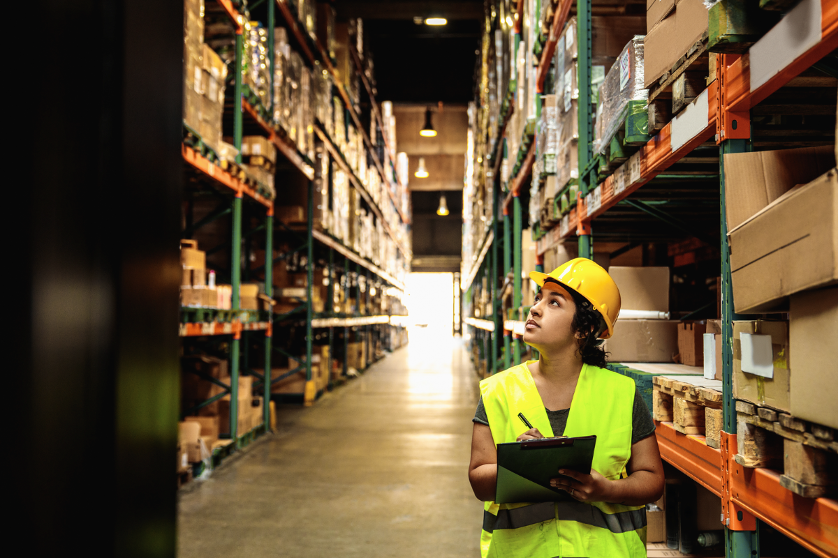 Warehouse woman worker checking pallet rack and boxes with clipboard