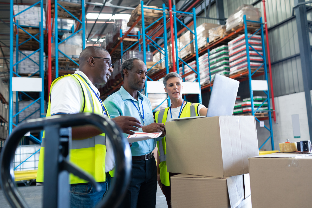 Workers discussing over laptop in warehouse